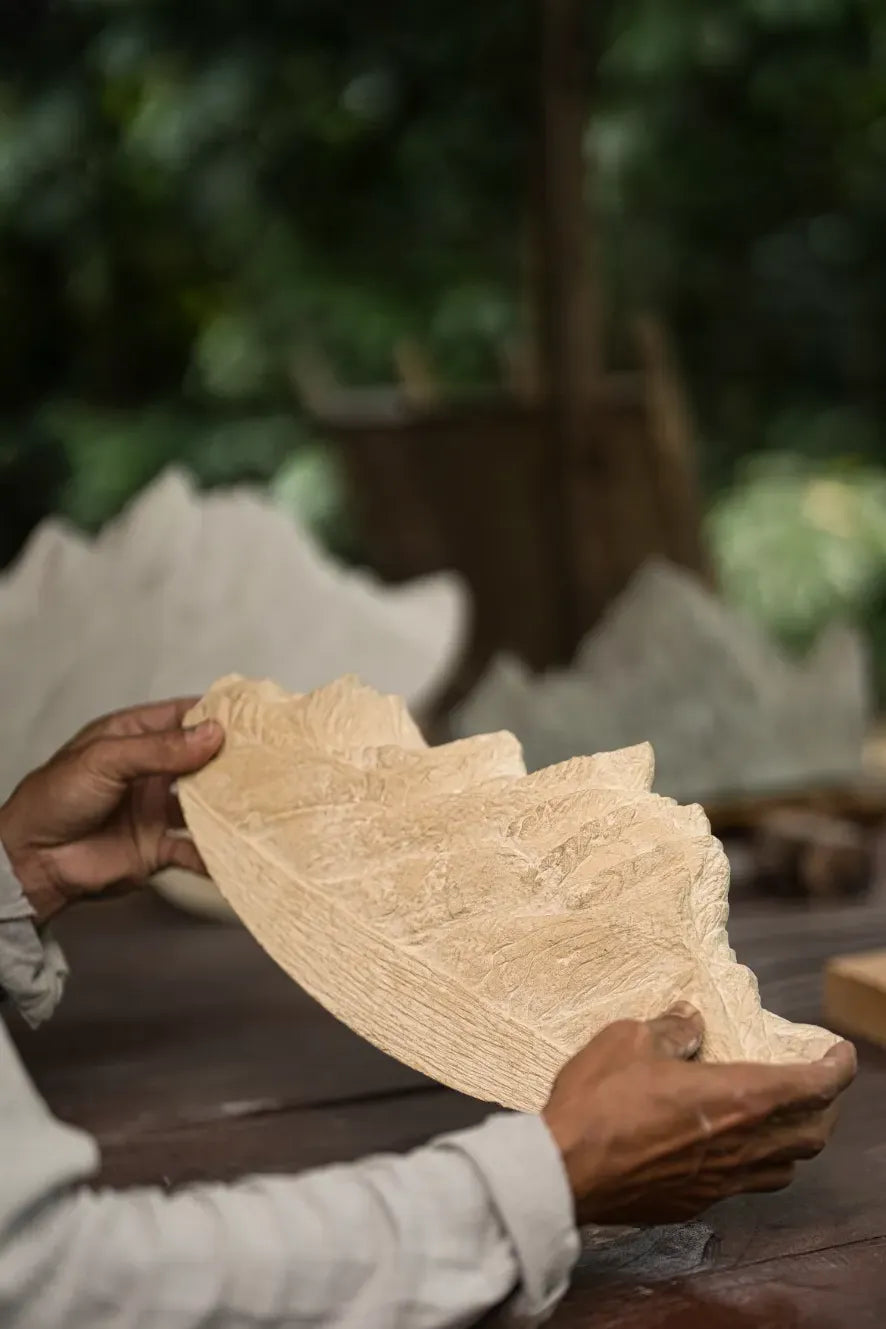 Person holding carved mountain sculpture beige with a blurred natural background