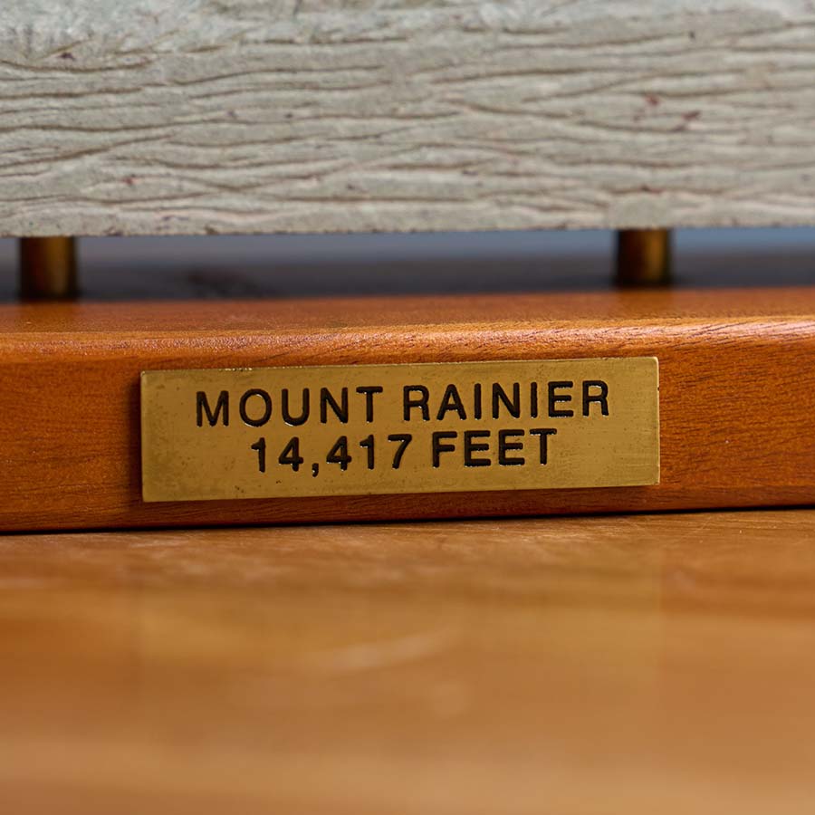 Close-up of a brass plaque engraving on a Mount Rainier sculpture, featuring the mountain’s name and elevation of 14,417 feet.